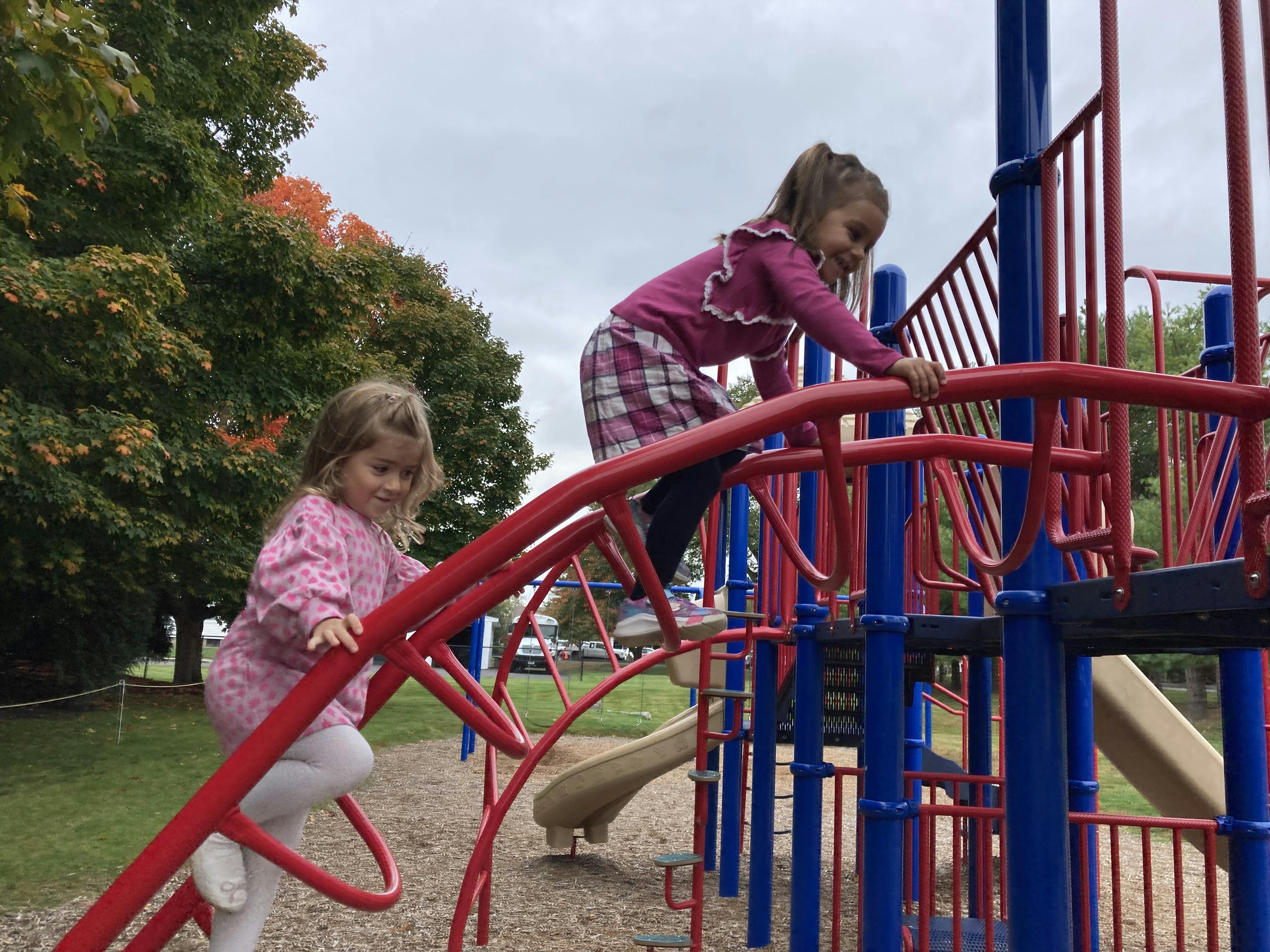 Two children climbing on playground equipment