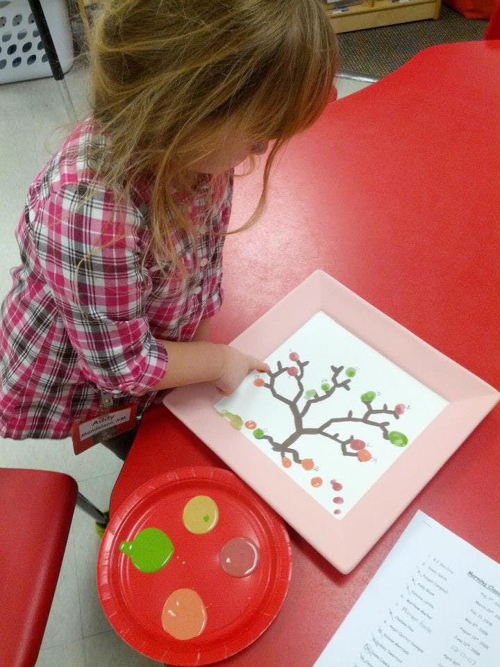 Child painting a tree with finger paints