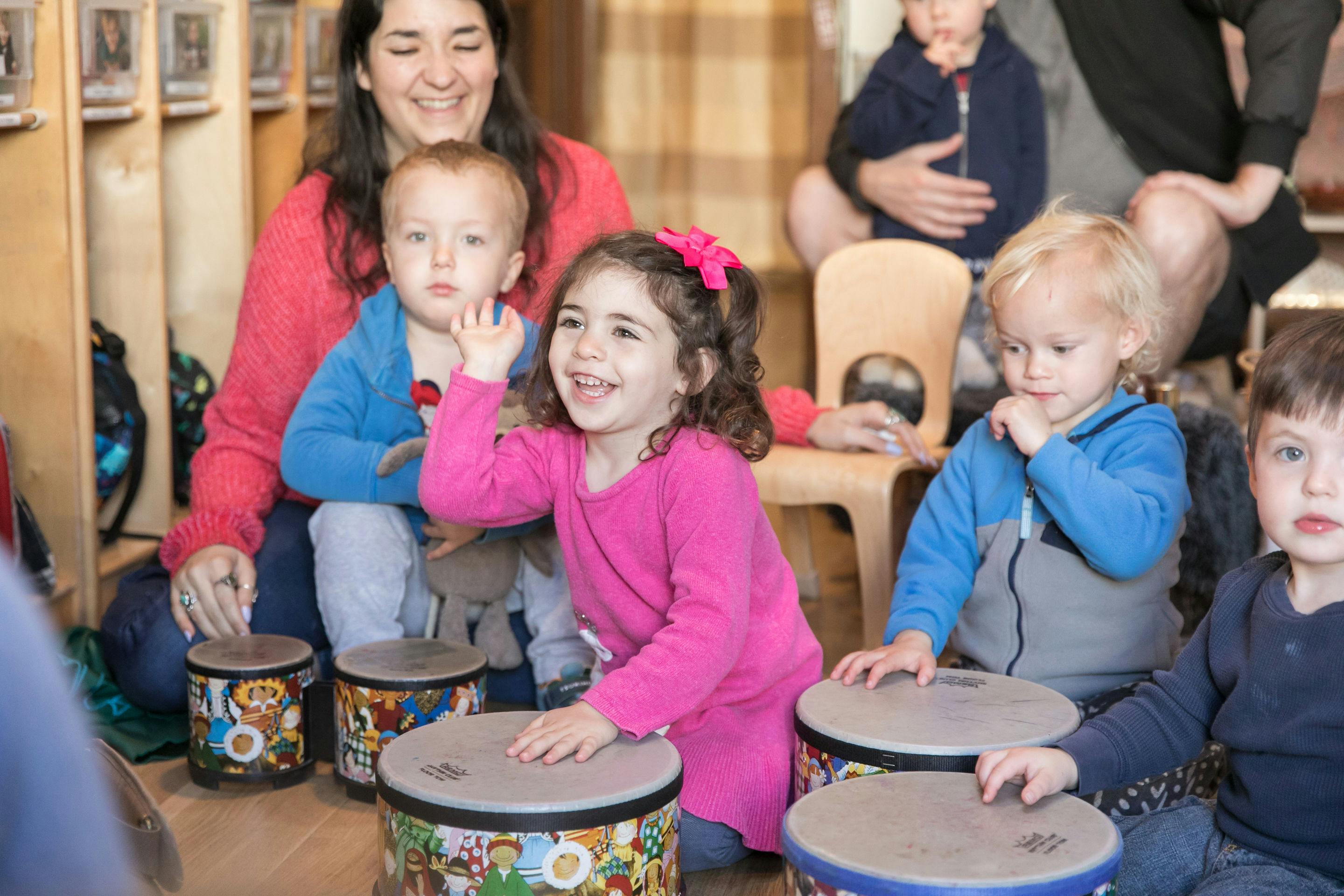 Adult and children playing drums in a classroom