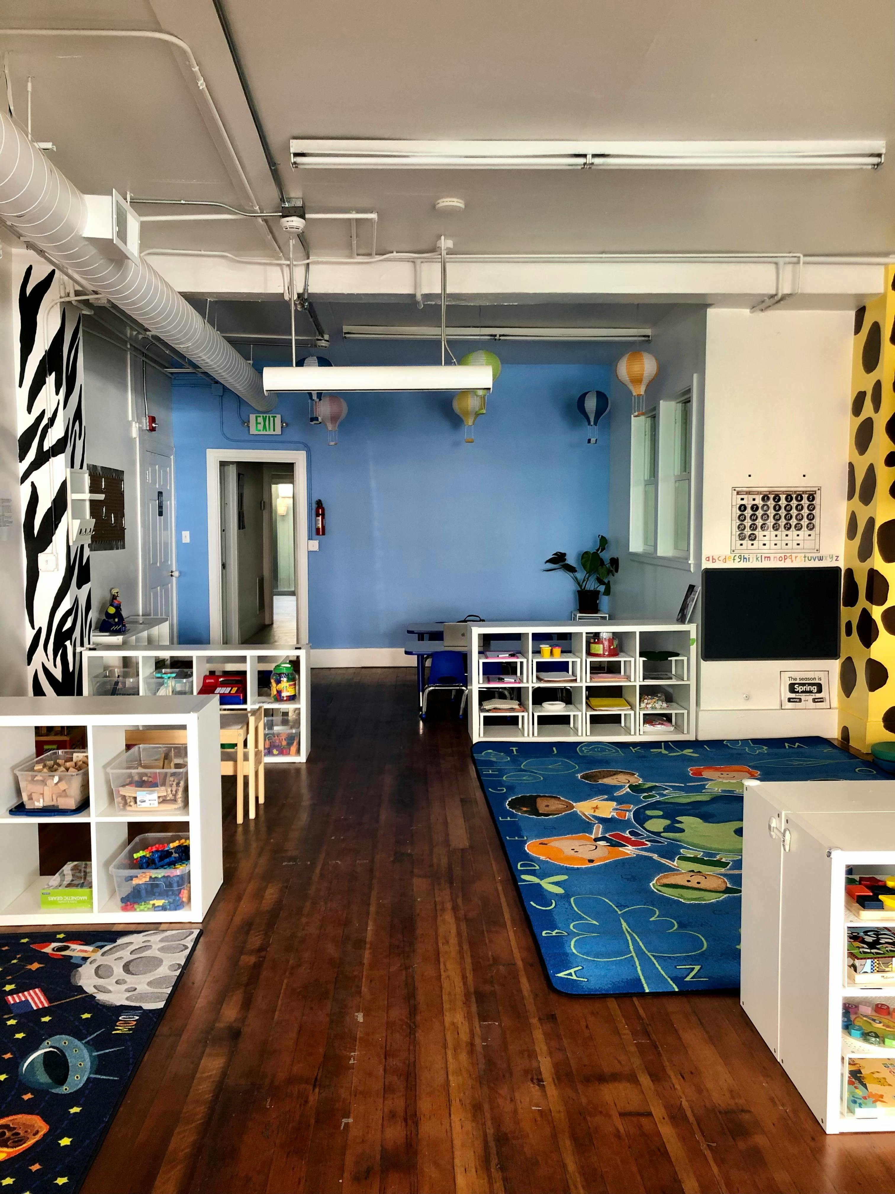 Classroom with blue walls, wooden floor, and white storage shelves