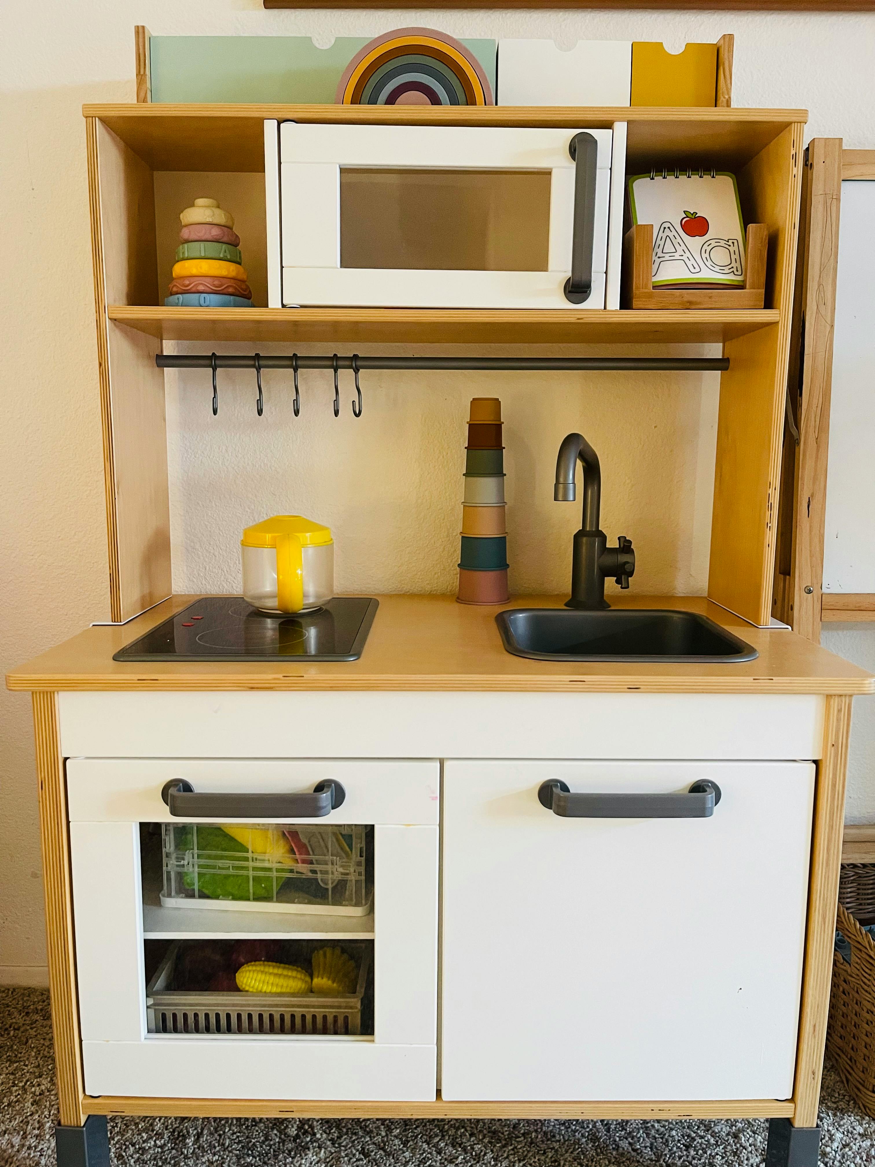 Child's play kitchen with microwave, stove, and sink