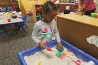 Child playing in a sand table with toys