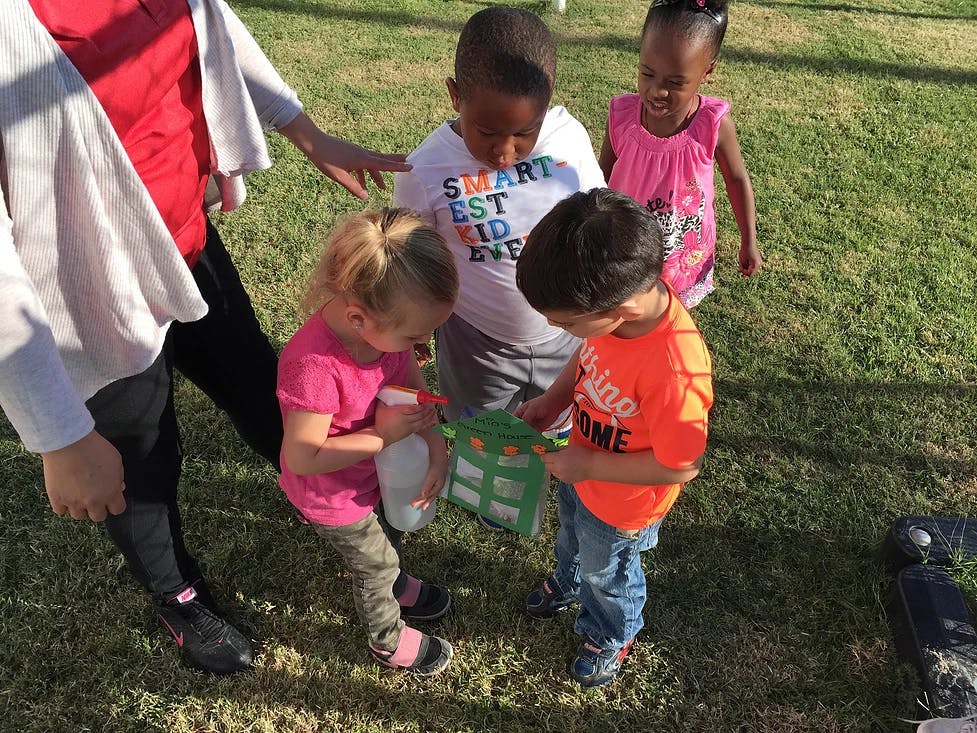 Adult and multiple children looking at a green object