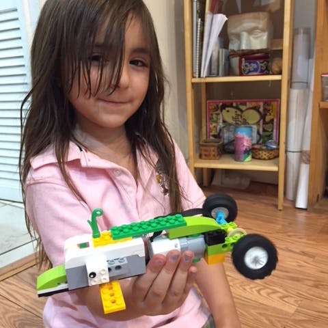 Child holding a toy car made of building blocks