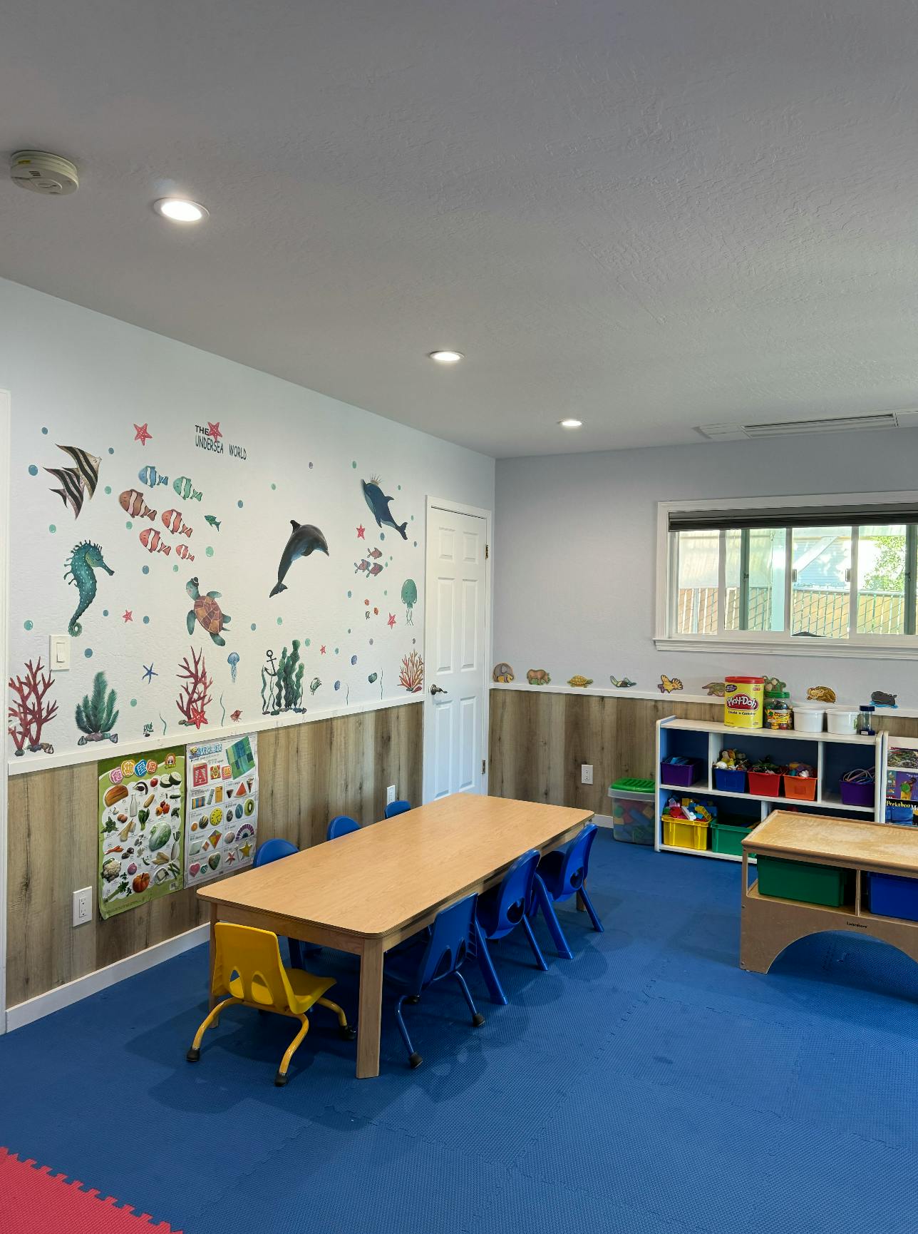 Classroom with a long table and chairs, ocean-themed wall decals