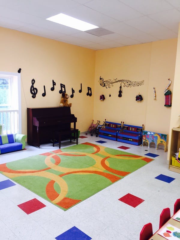 Music-themed classroom with a piano, colorful rug, and musical notes on the wall