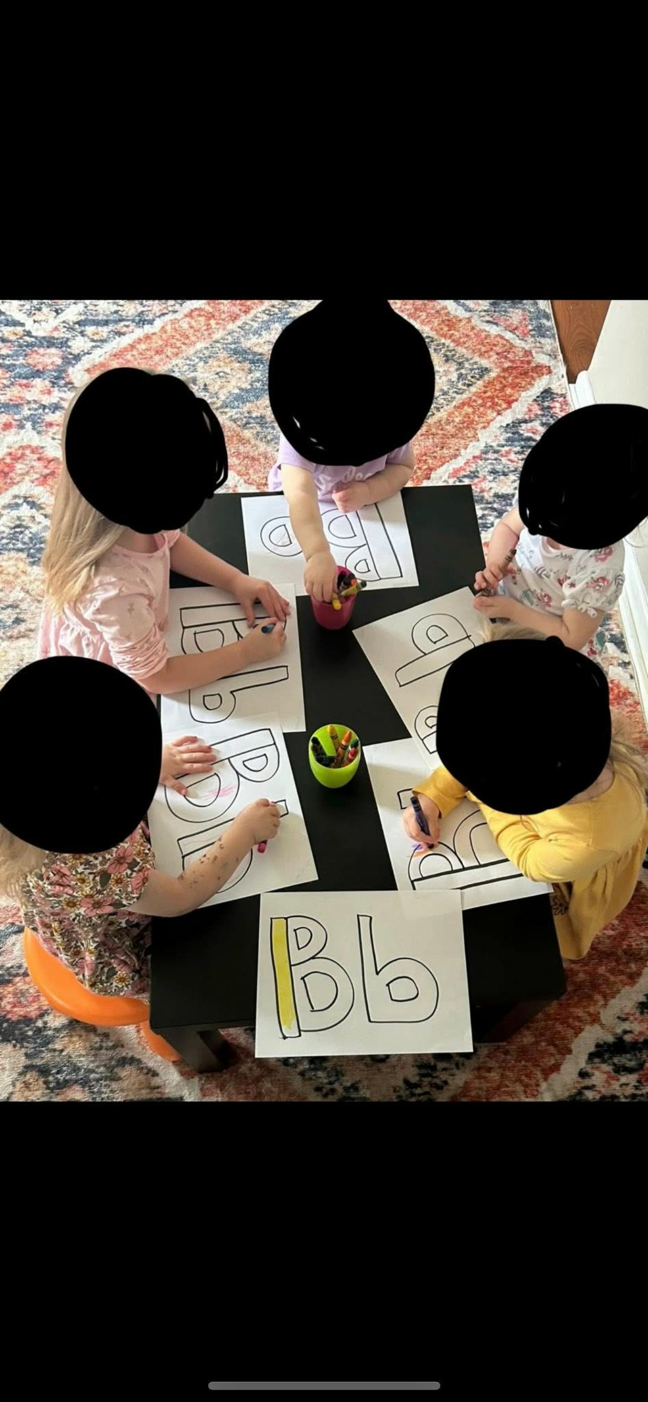 Children coloring letter B worksheets at a table