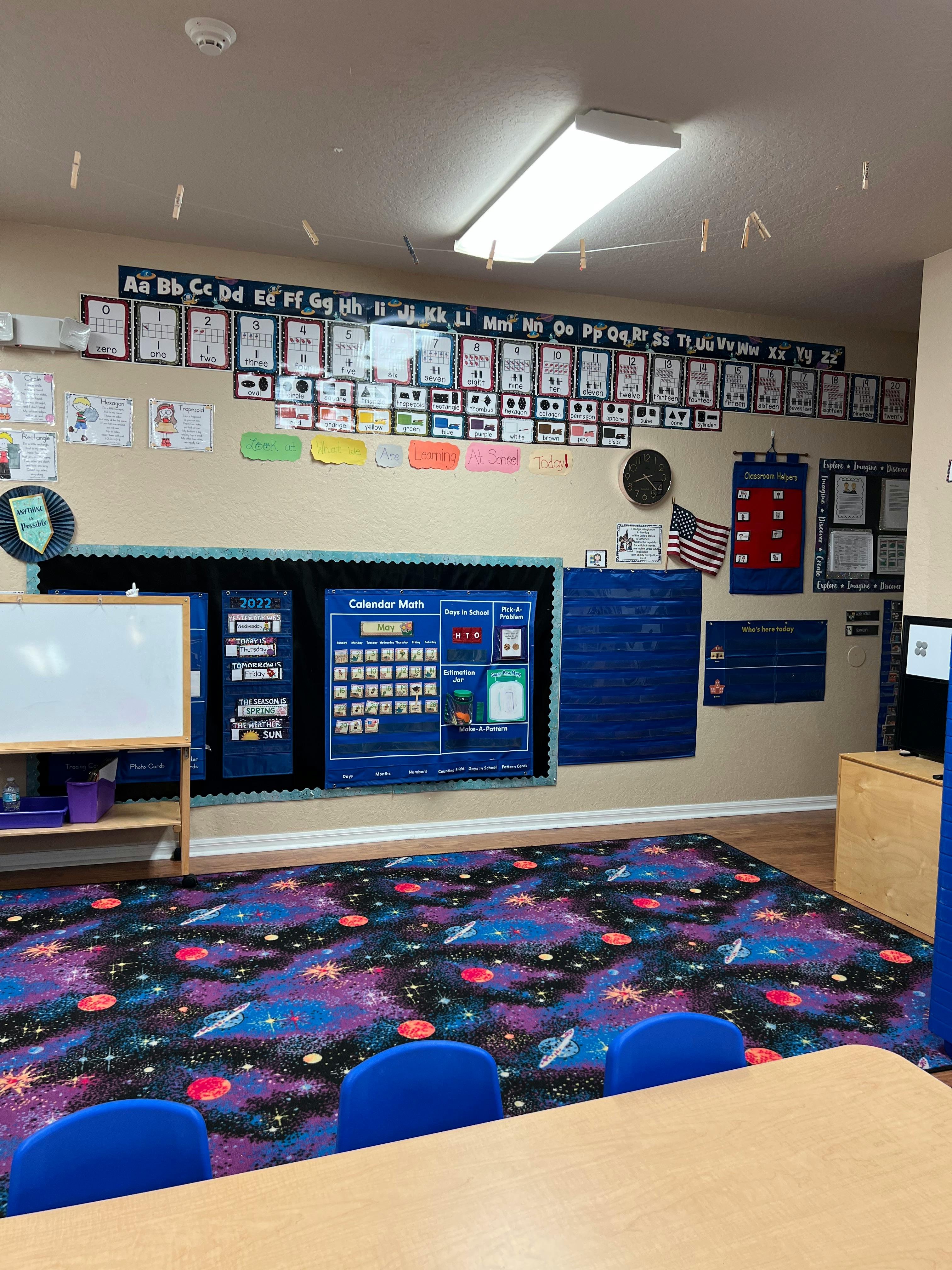 Classroom with alphabet display, calendar, whiteboard, and space-themed carpet