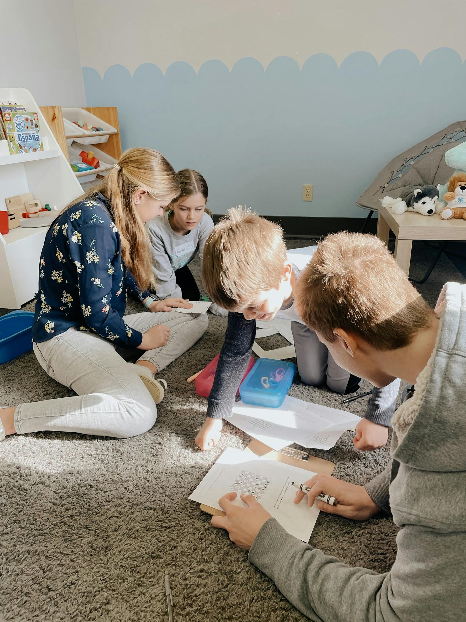 People and children sitting on a rug looking at papers