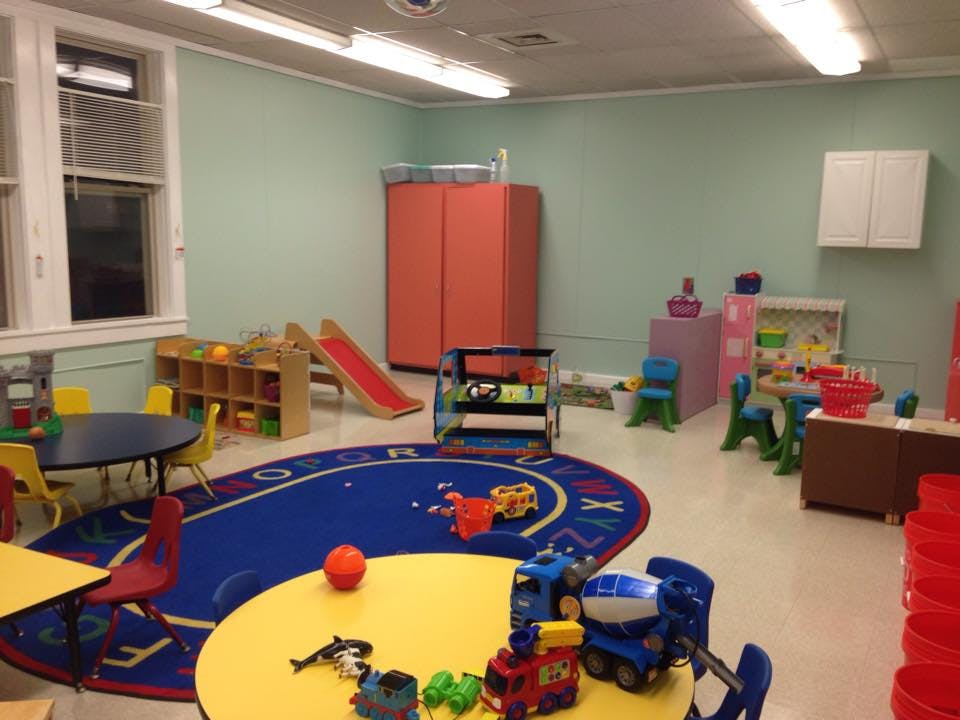 Playroom with tables, chairs, toys, and a small slide