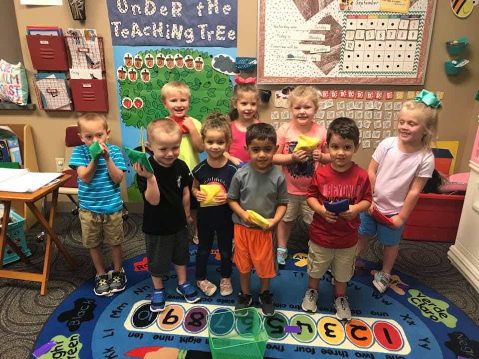 Group of children holding small objects in a classroom