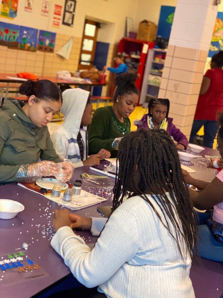 People and children sitting at a table doing crafts