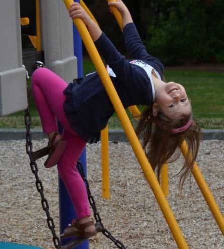 Child hanging upside down on playground equipment