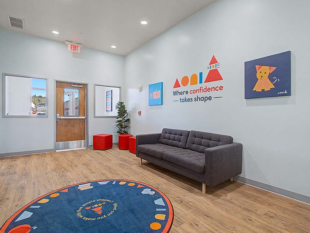 Lobby with a gray sofa, red cube ottomans, and a round blue rug