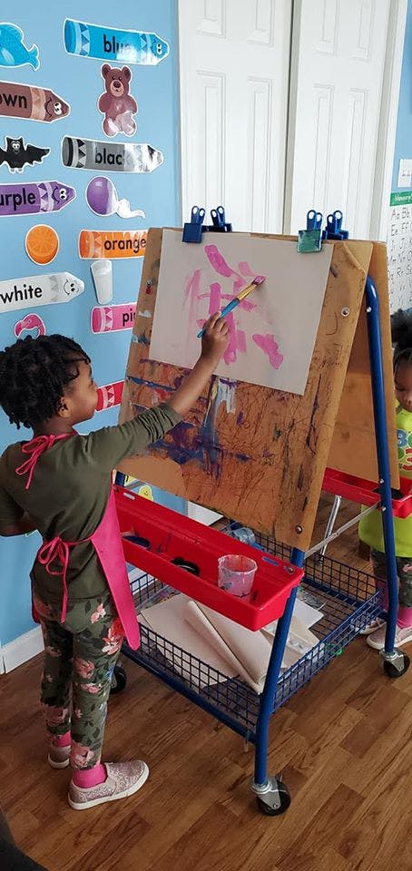 Child painting on an easel in a classroom