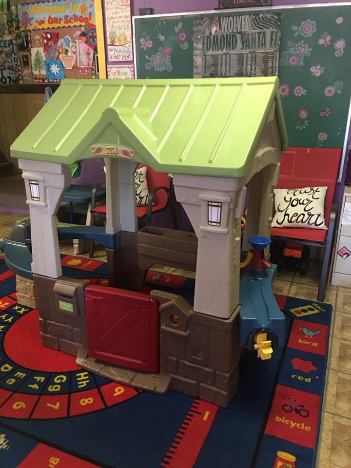 Plastic playhouse with green roof on a colorful rug