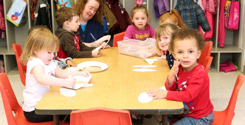 Adult and children sitting at a table in a classroom