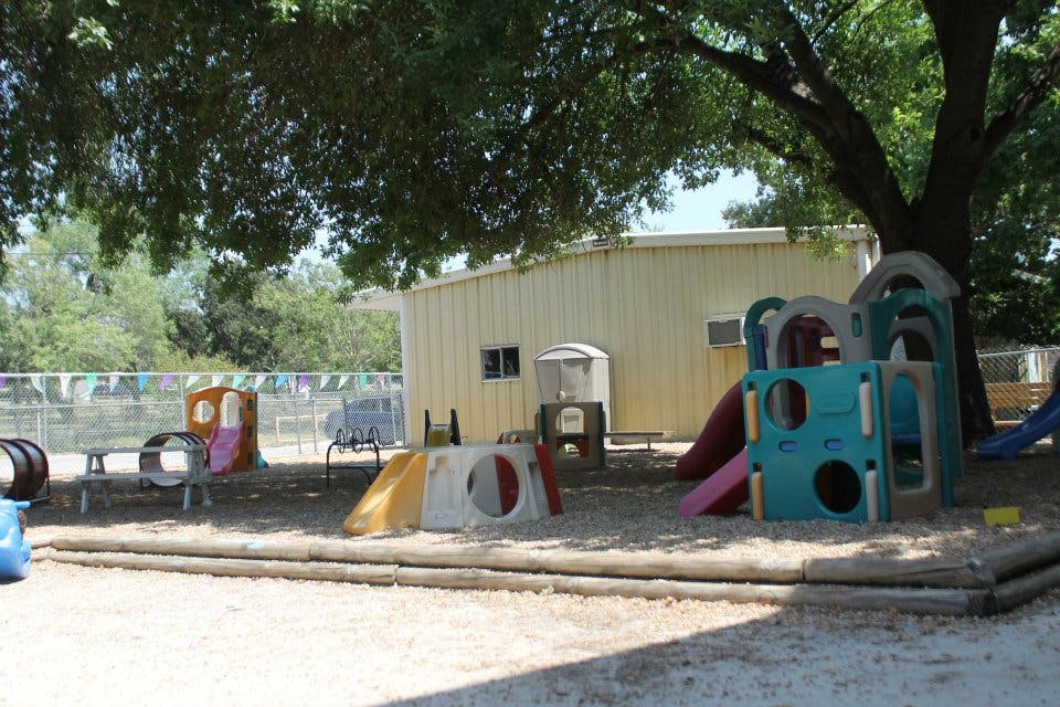 Outdoor playground with various play structures and a building in the background
