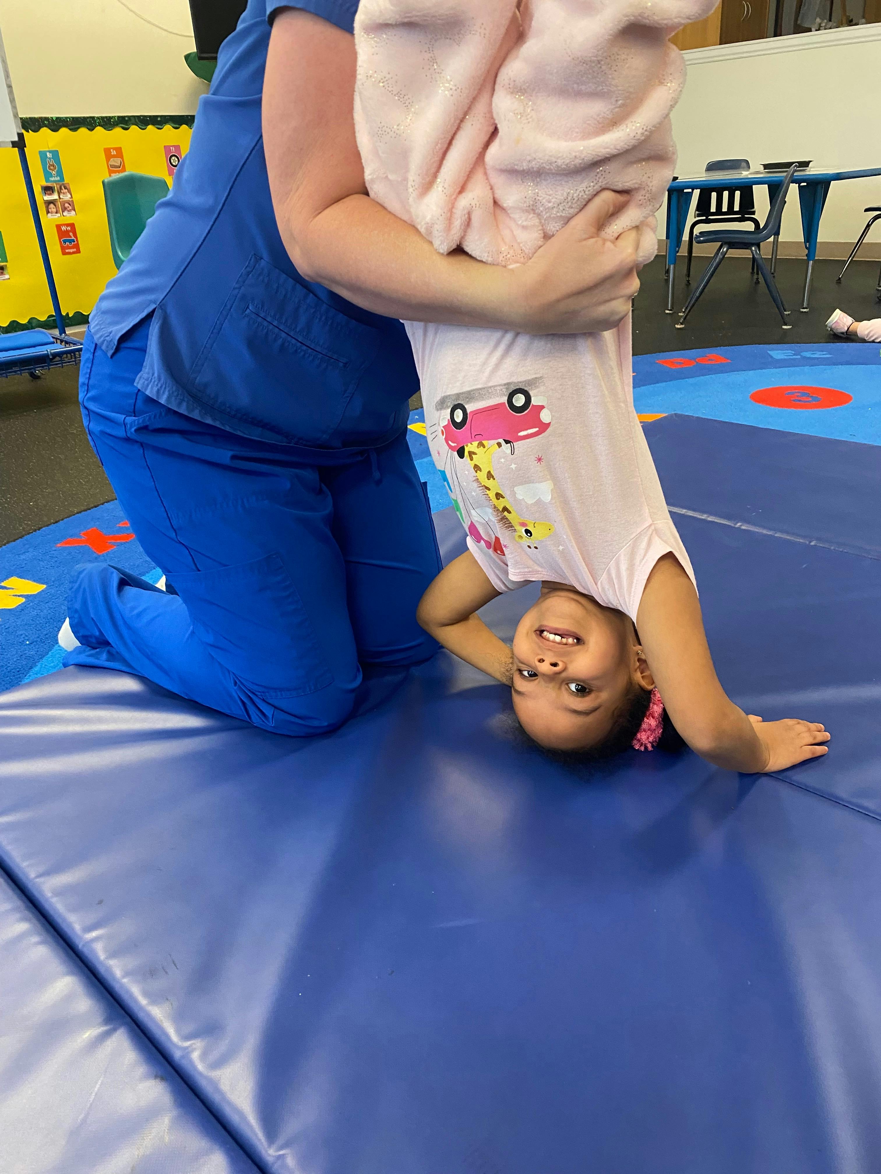 Person holding a child upside down on a blue mat