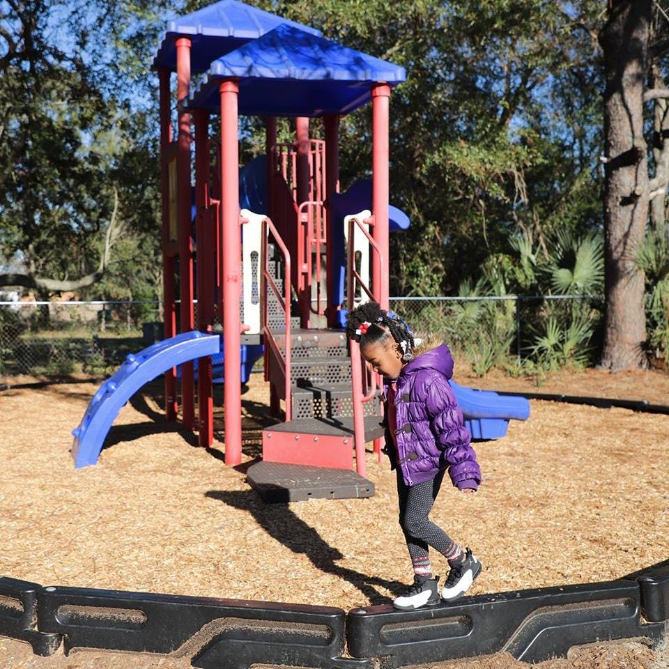 Child walking on a playground near a play structure
