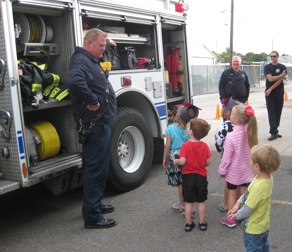 Firefighter talking to a group of children next to a fire truck