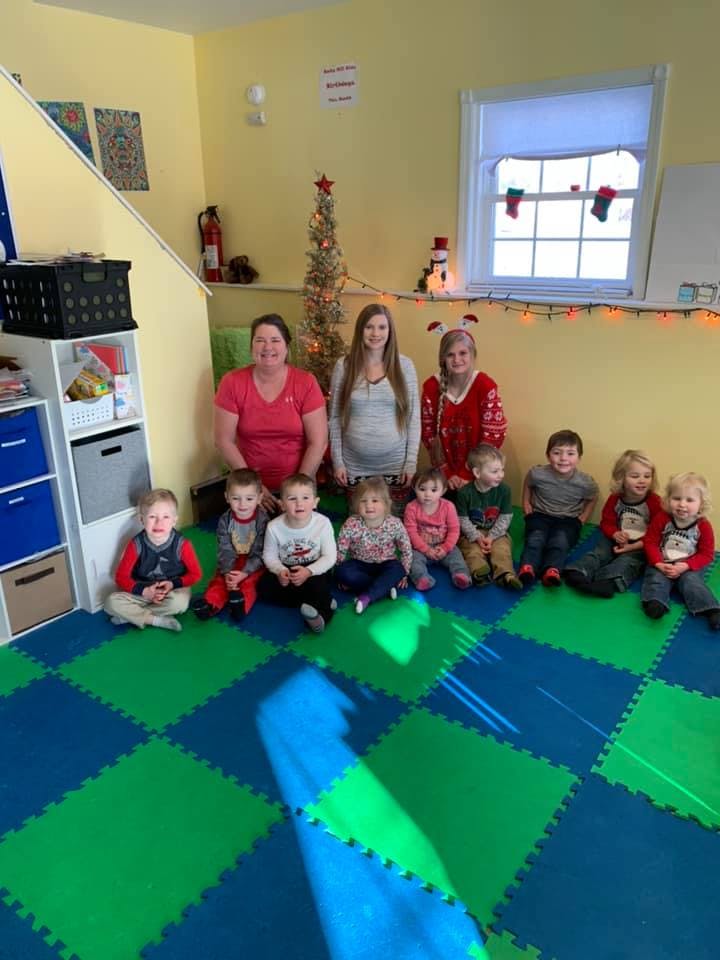Three adults and multiple children posing for a photo in a classroom