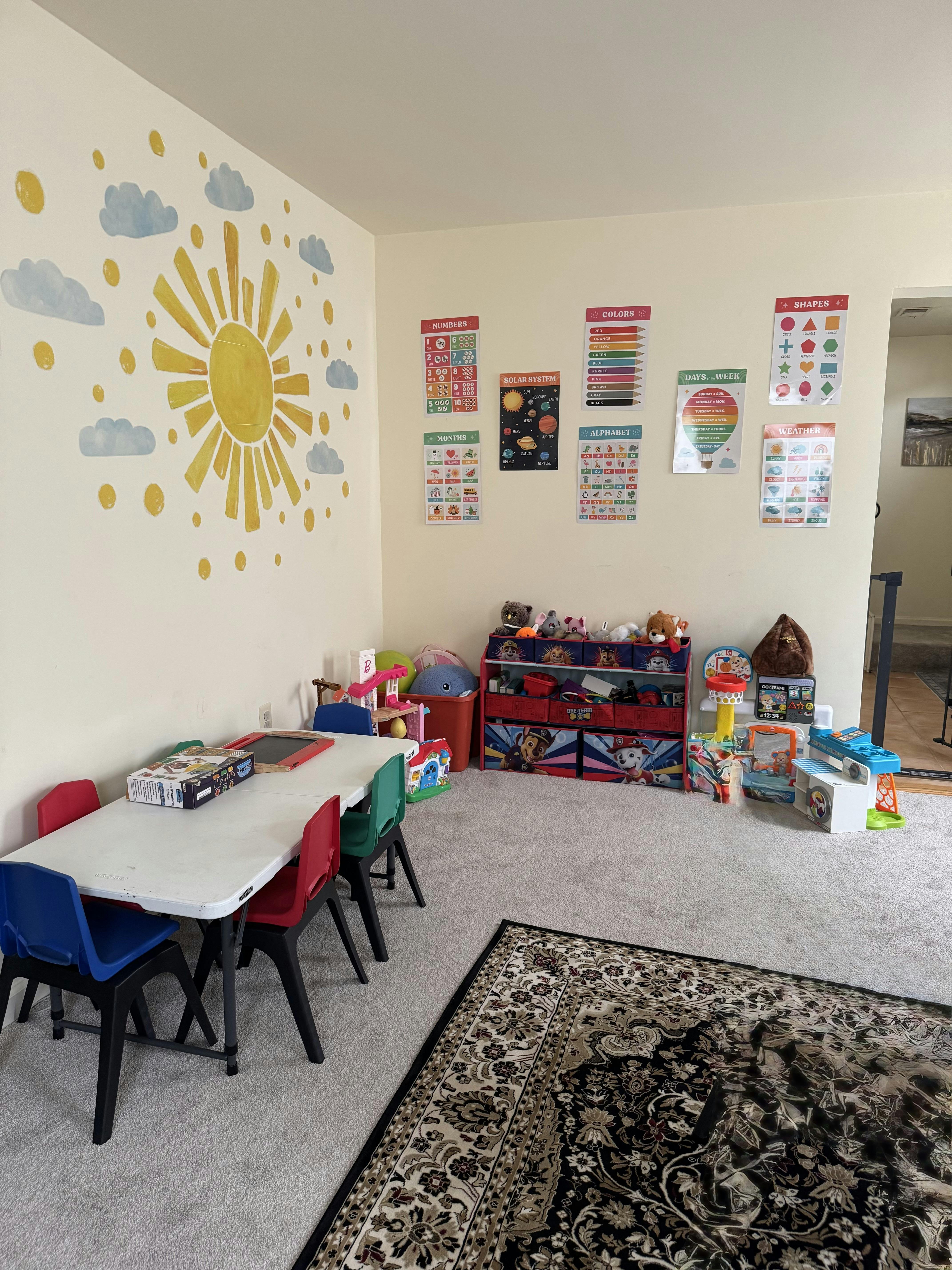 Playroom with a table and chairs, toy storage, and educational posters on the wall