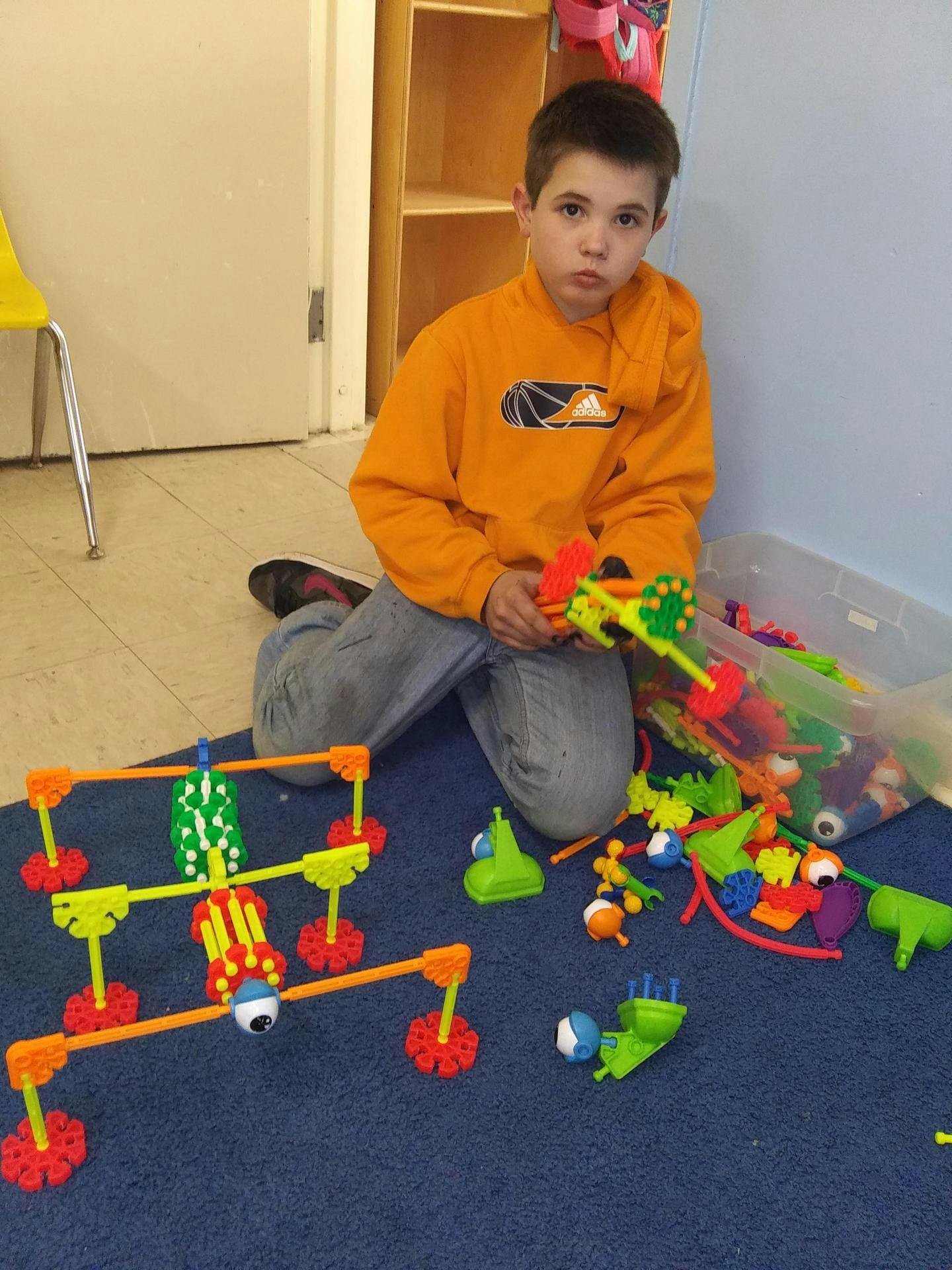 Child kneeling on floor playing with colorful building toys