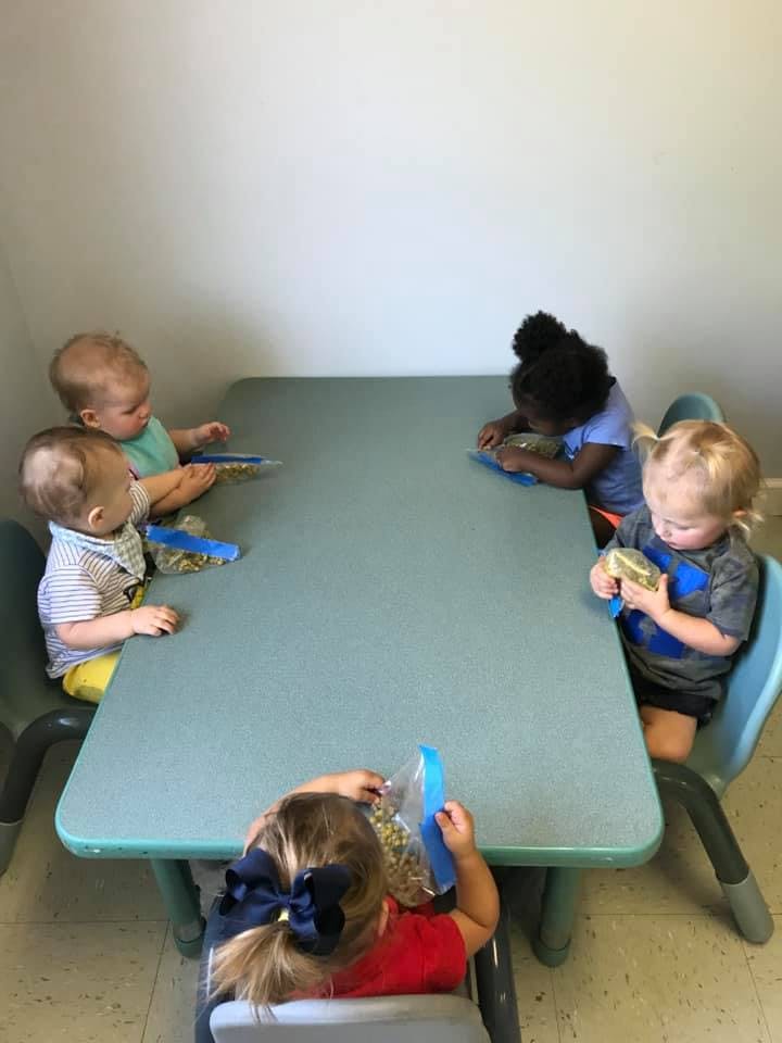 Four children sitting at a table with bags of snacks