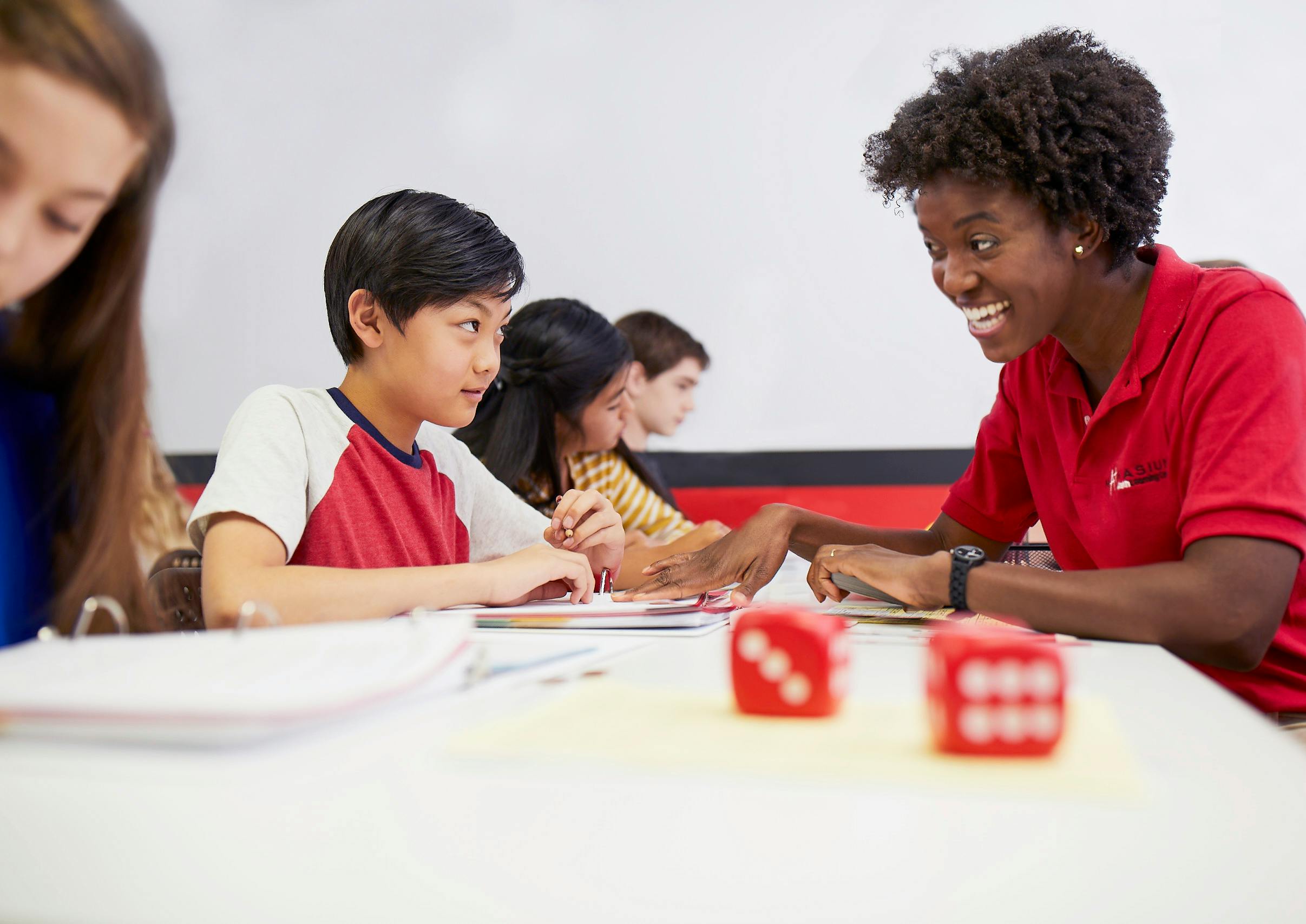 Adult and child seated at desk with two other children in background