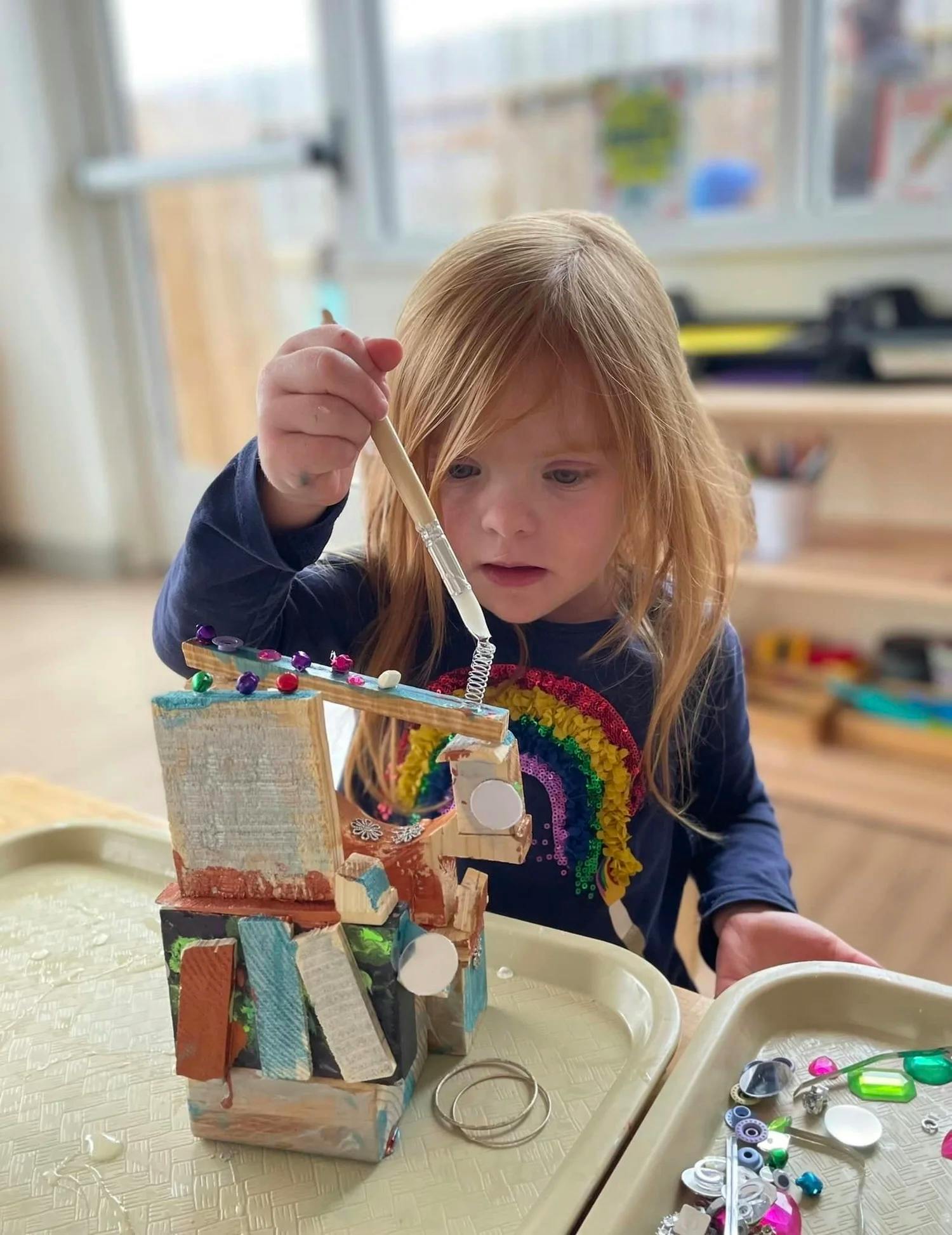 Child applying glue to a small wooden craft sculpture