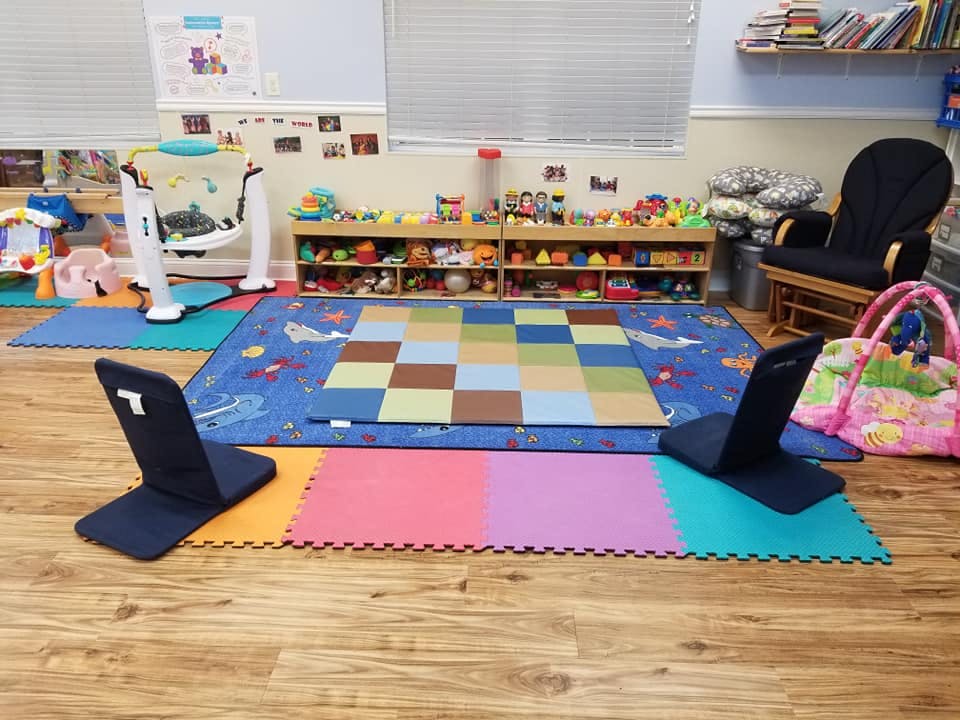 Playroom with colorful mats, toys on shelves, and a rocking chair