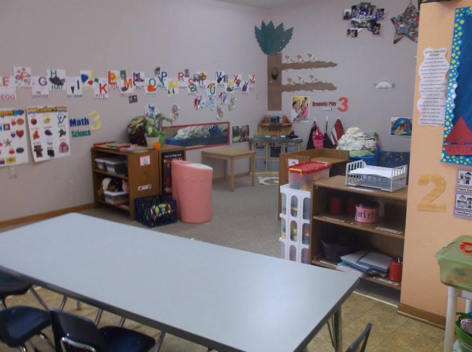 Classroom with tables, chairs, and shelves with learning materials