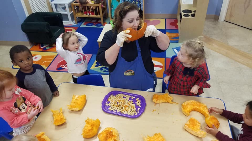 Adult and children at a table with pumpkin pieces and seeds
