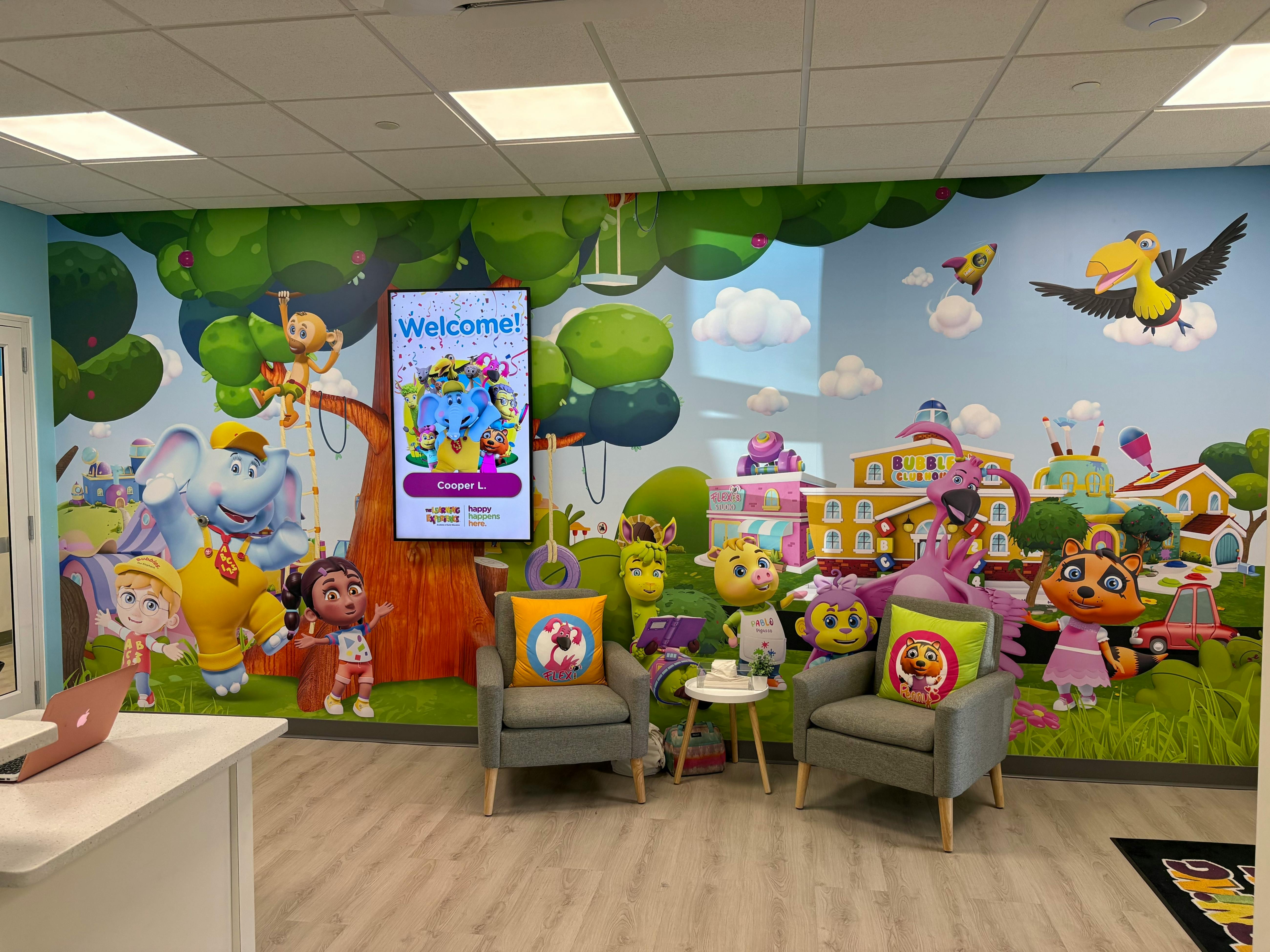 Waiting room with cartoon mural and two chairs with character pillows