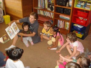 Person reading a book to children in a room