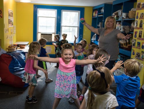 Adult and children playing with bubbles in a classroom