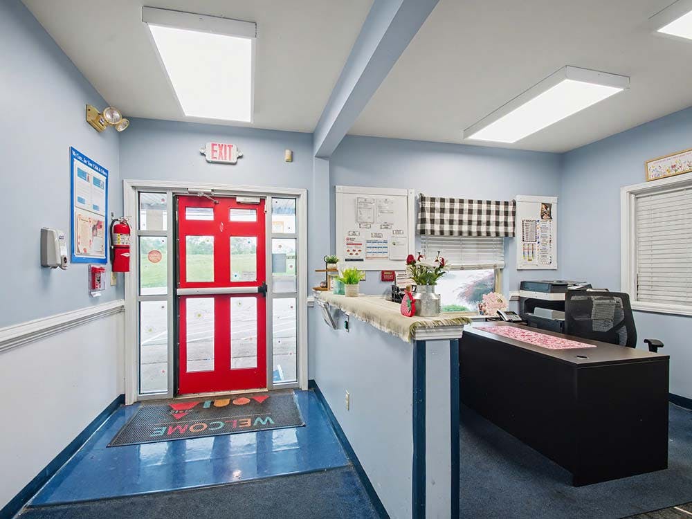 Reception area with a red double door and a desk