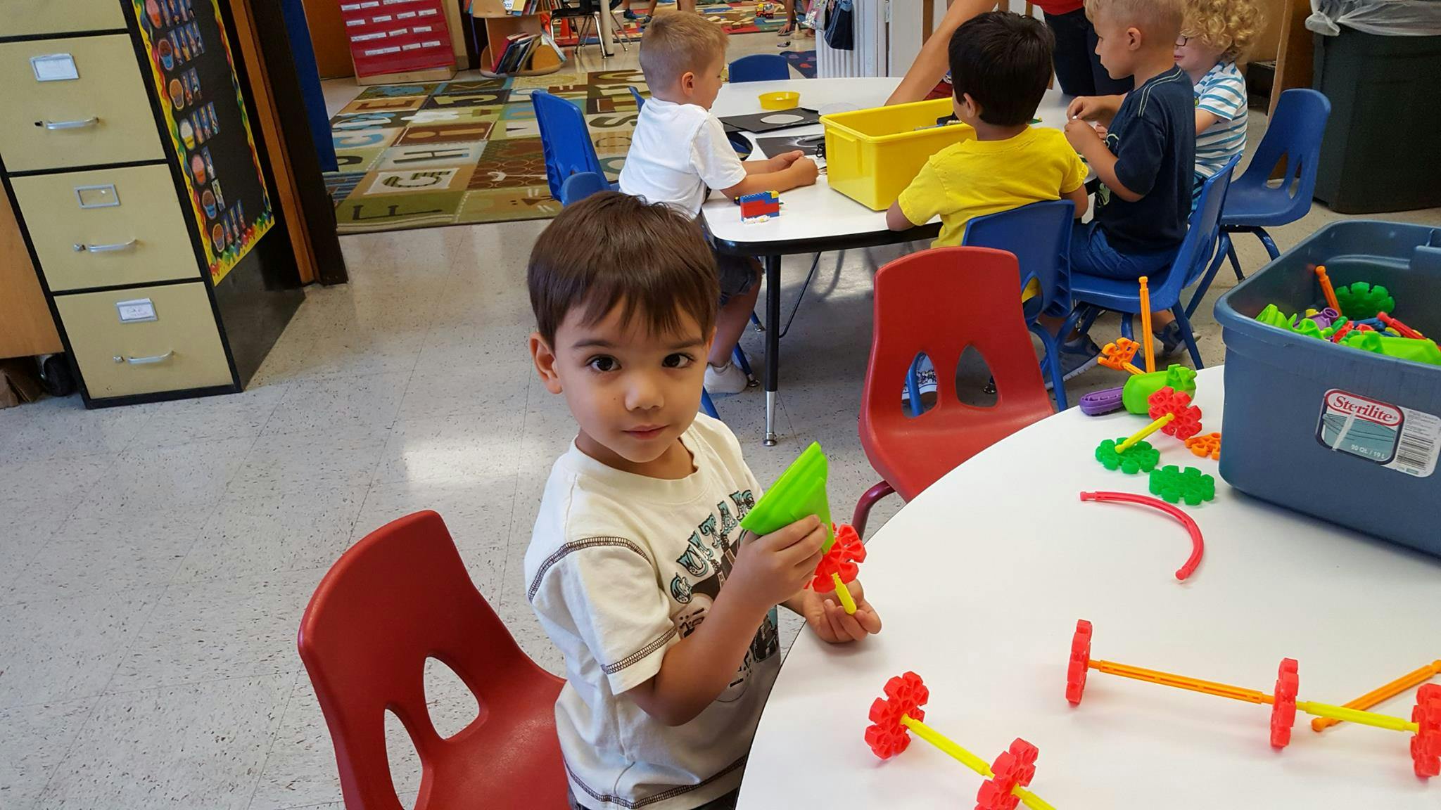 Child playing with building toys at a table in a classroom