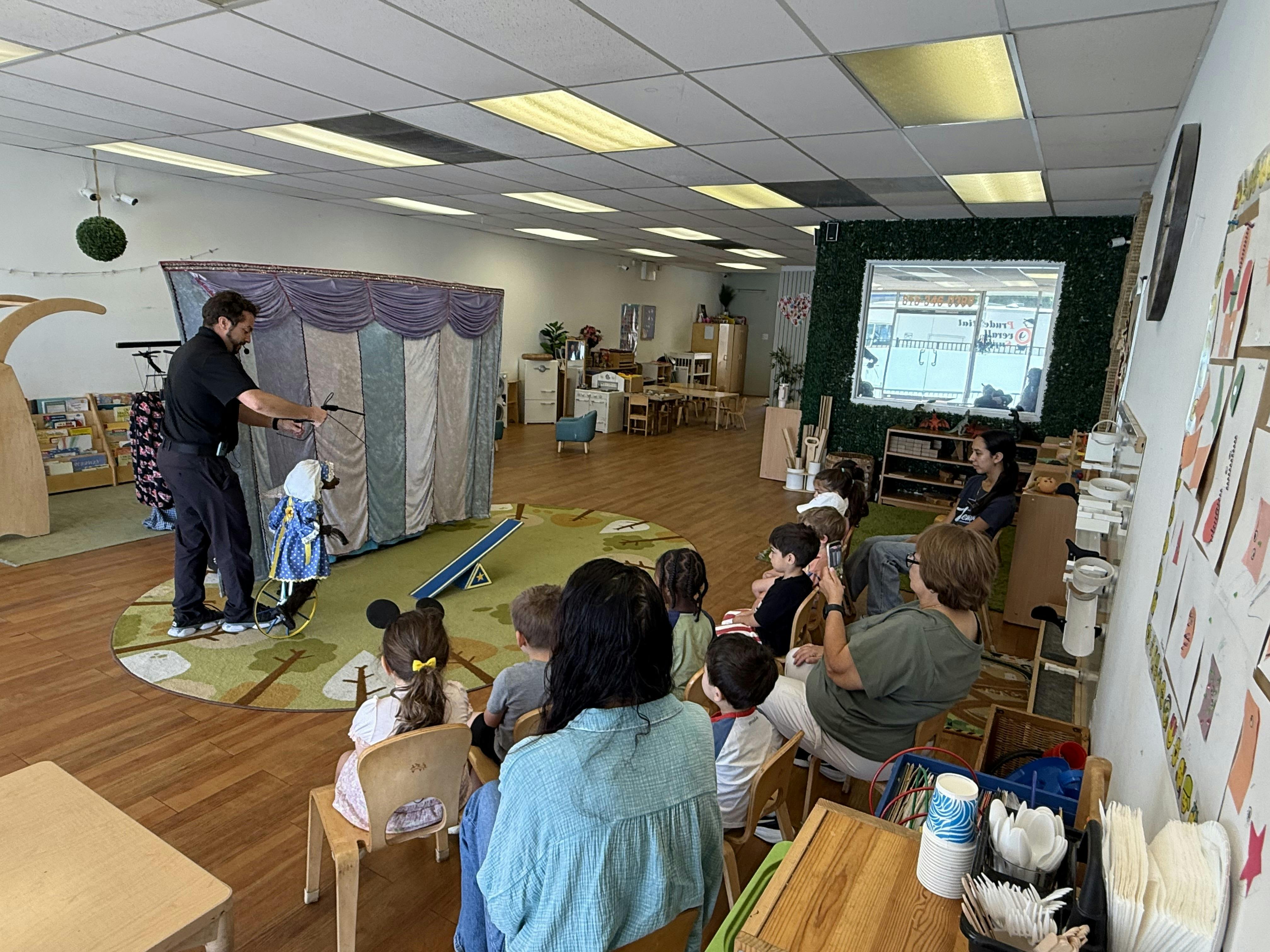 Performer operating a marionette for an audience of people sitting in a classroom
