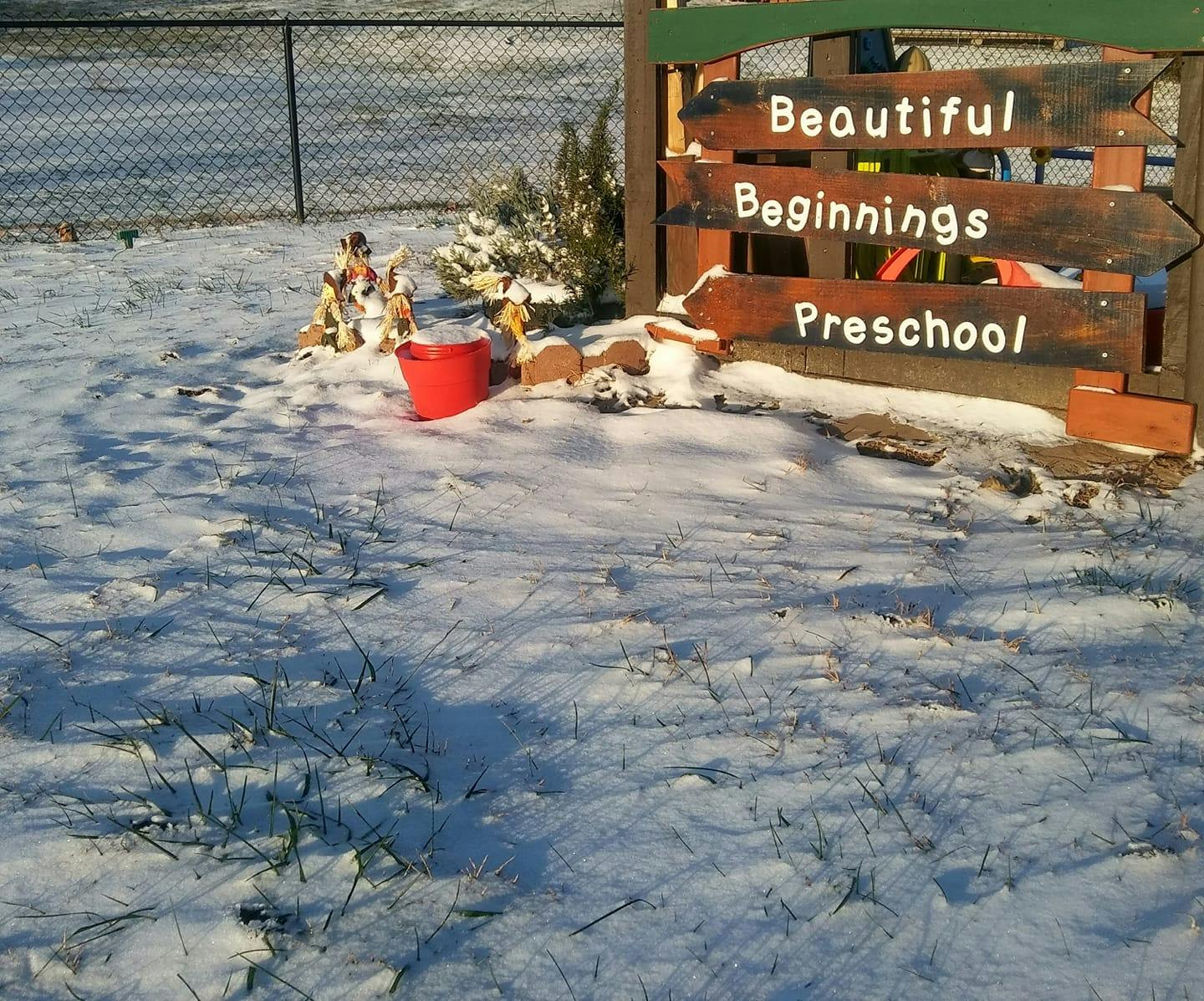 Snowy ground with a wooden sign reading "Beautiful Beginnings Preschool"