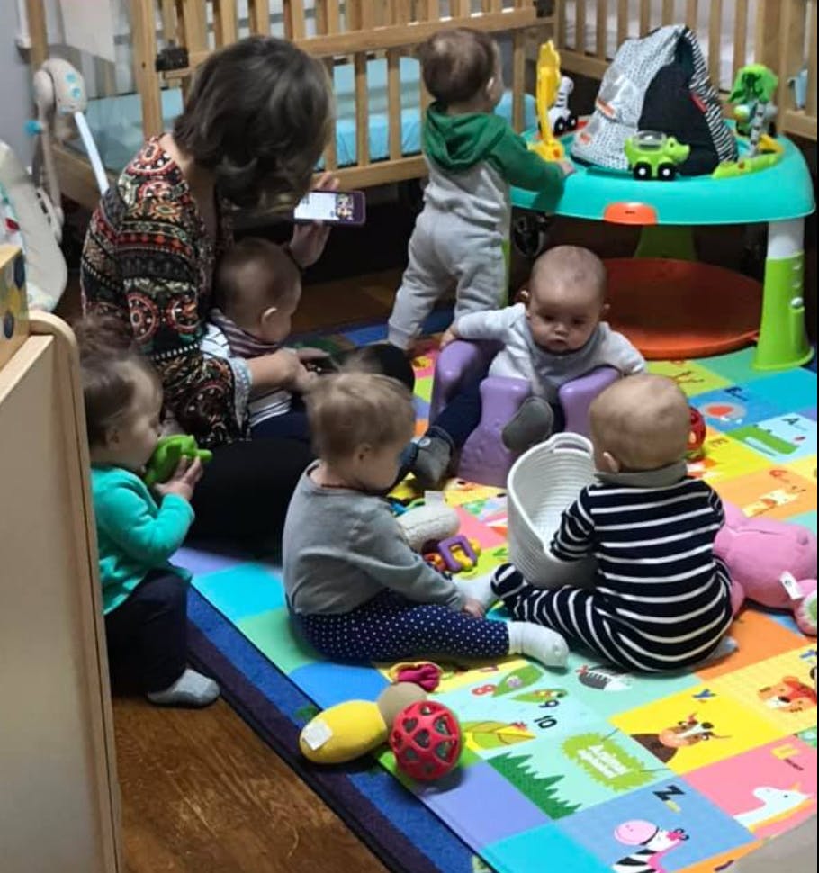 Person with multiple children playing on a colorful mat