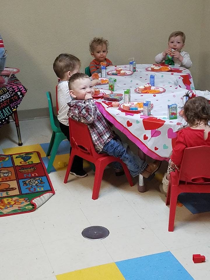 Children sitting at a table with a heart-patterned tablecloth