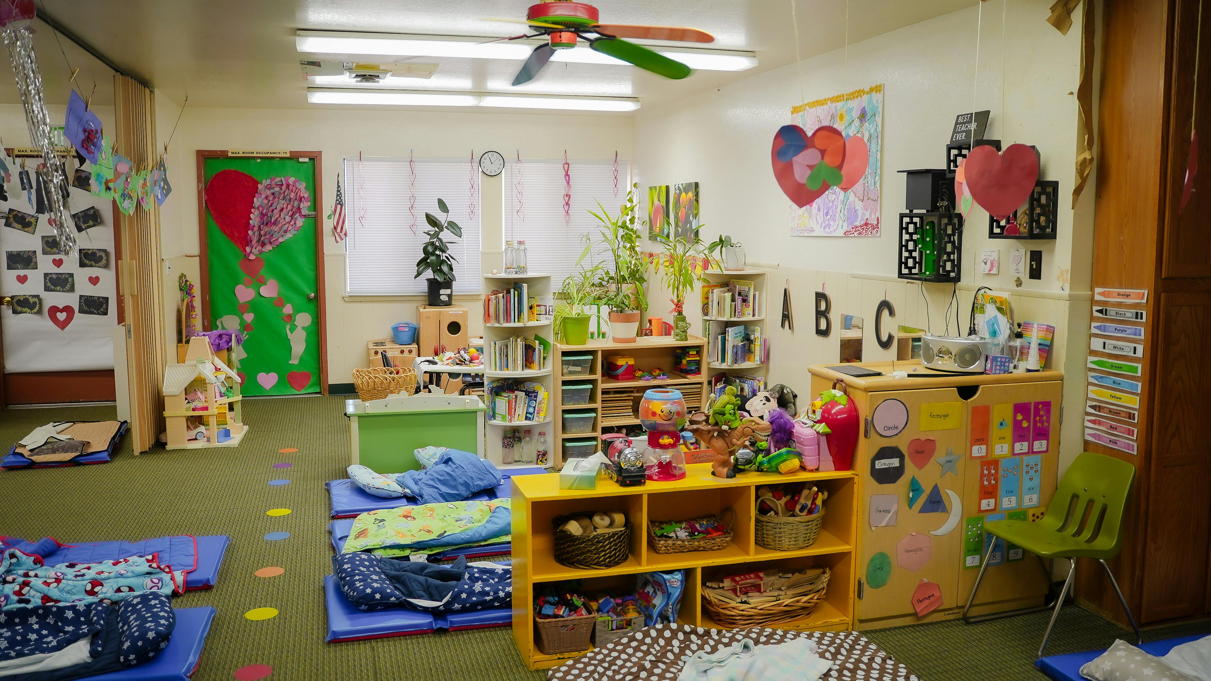 Colorful preschool classroom with toys, books, and nap mats on the floor