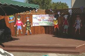 Outdoor stage with paper cutouts of children and a banner that reads "Congratulations"