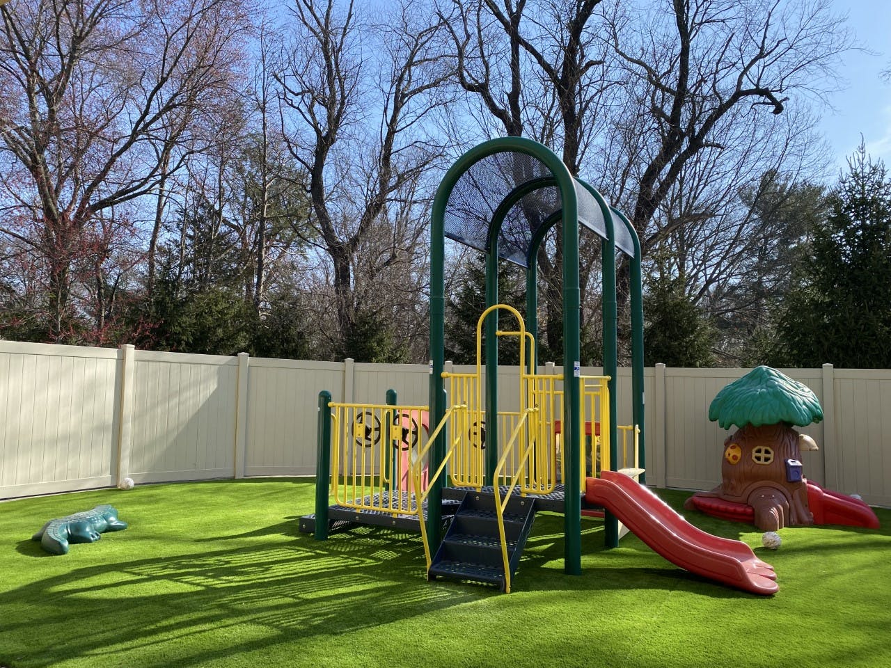Playground with green and yellow play structure and red slide
