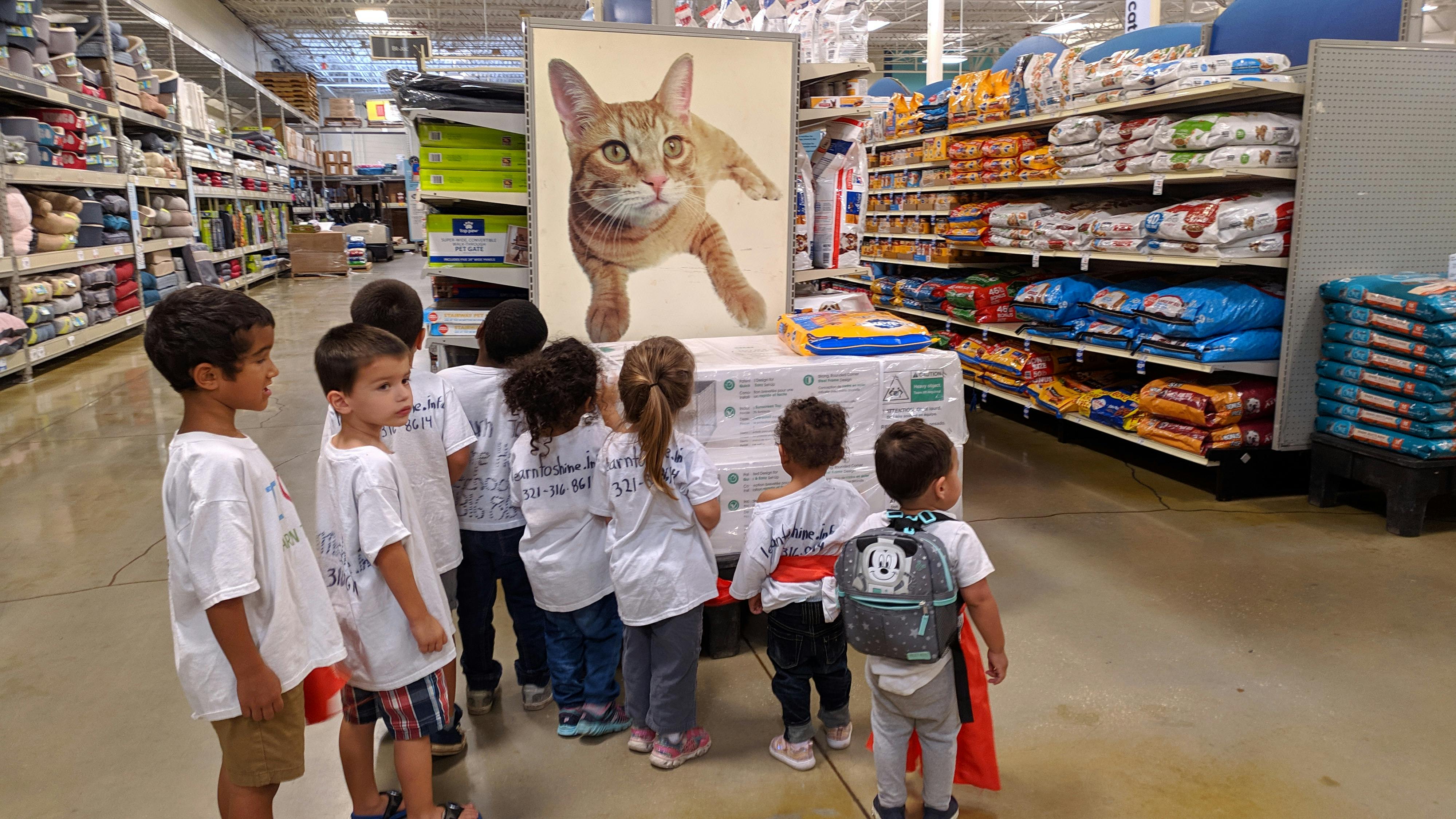 Children looking at a large cat image in a store aisle