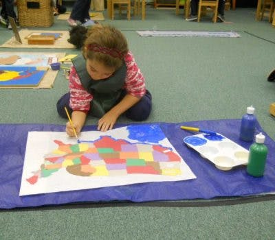 Child painting a map on the floor