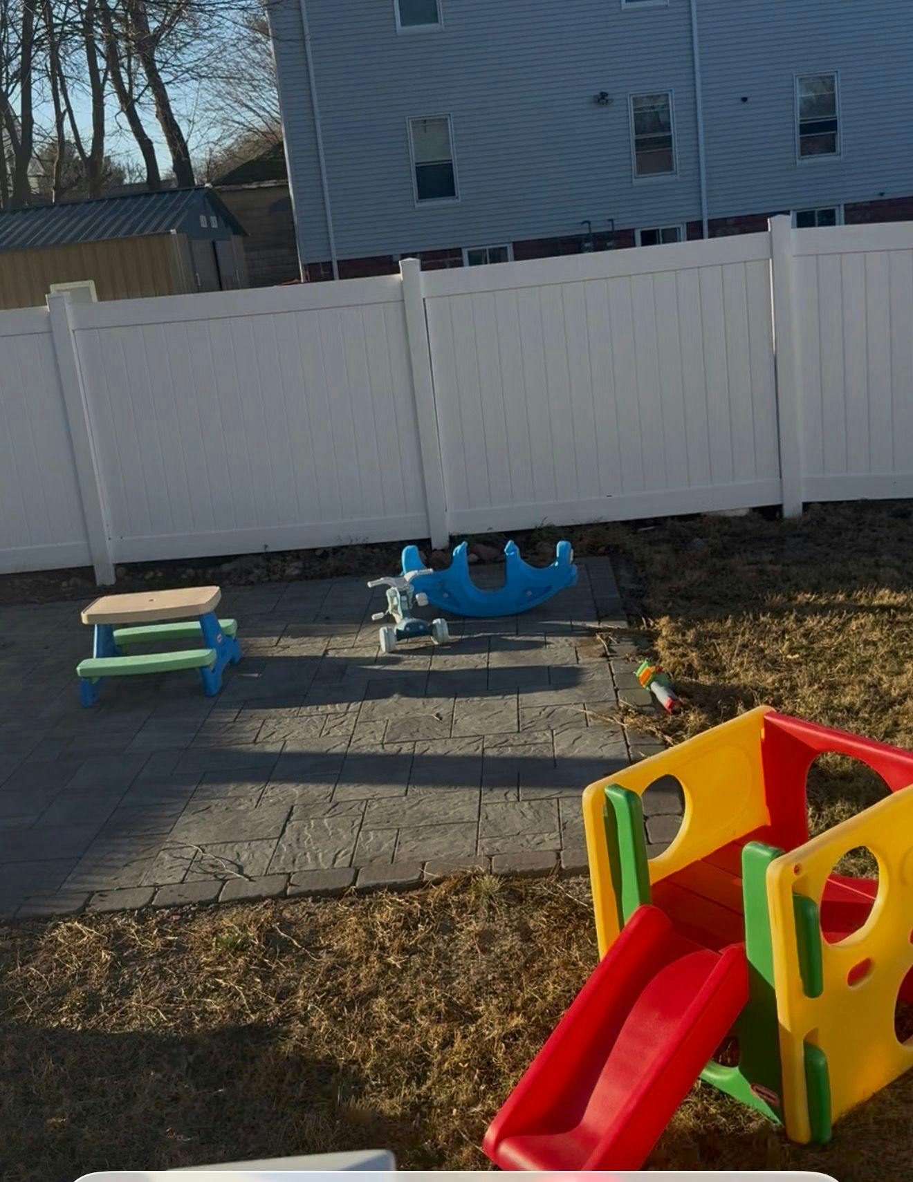 Children's playground area with a small picnic table, rocker, and slide