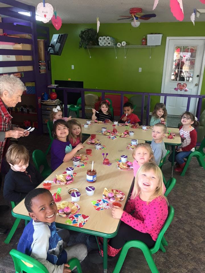 Adult and children seated at tables in a classroom